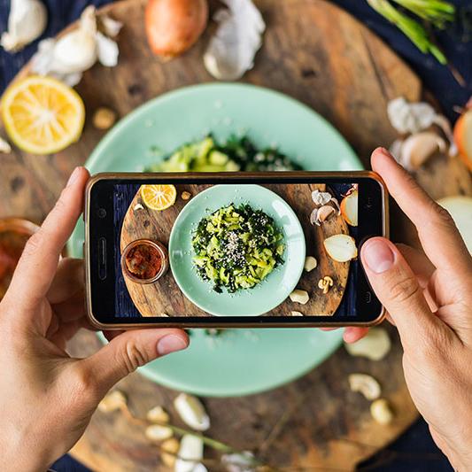 Phone view of someone taking a photo of a vegetarian dish.